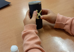 Dziewczynka przykleja godło górnicze do obklejonej czarnym papierem rolki